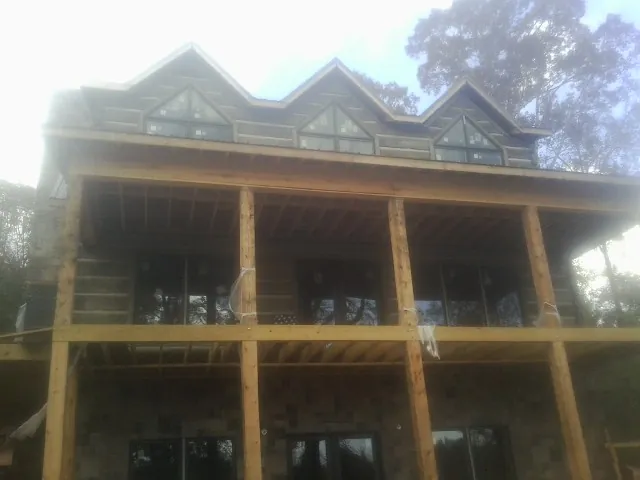 Dormers and porch framing on a large log home under construction — Roof Coating work by our crew in De Mossville