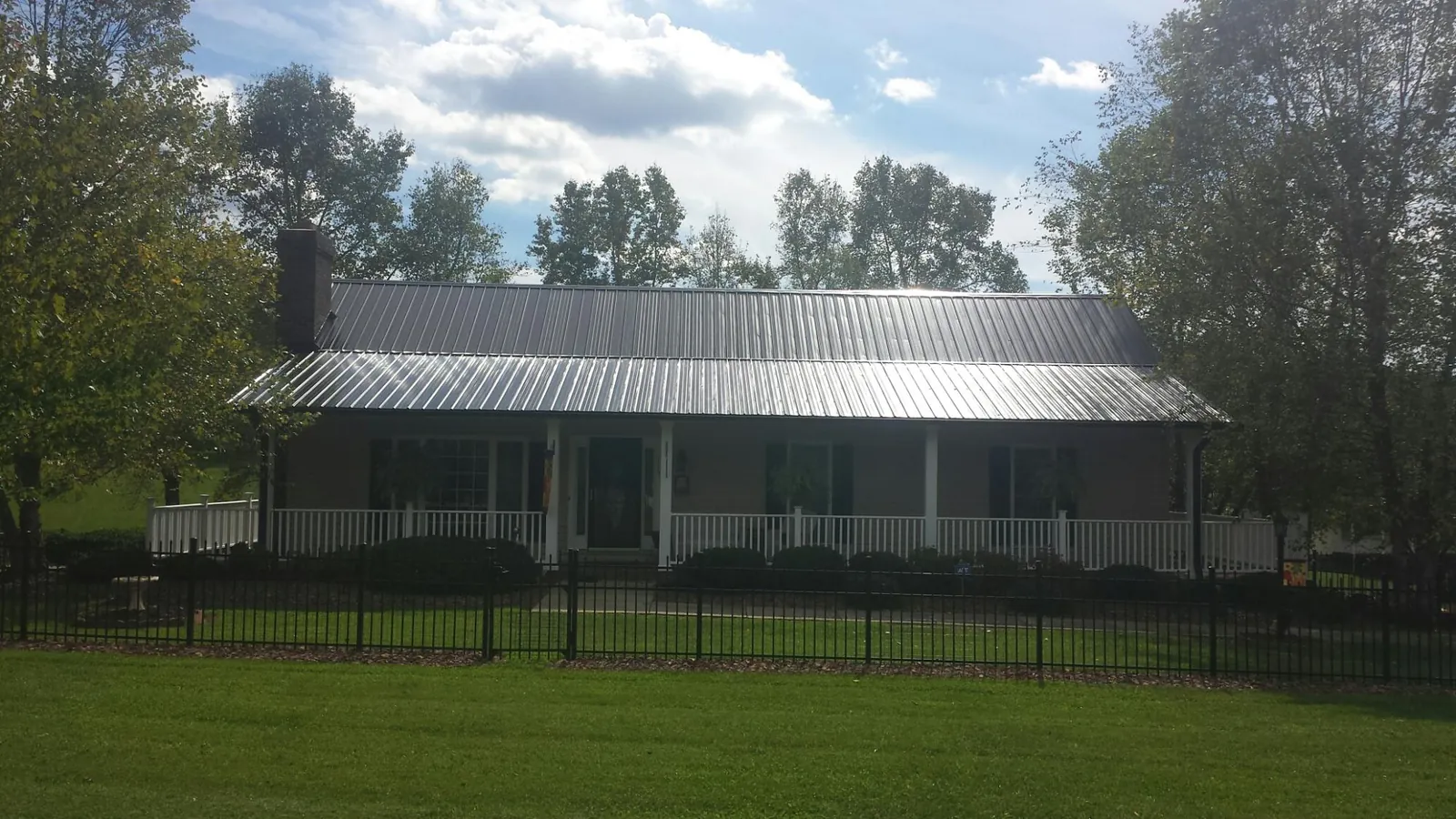 Gray metal roof on a brick ranch with a full width front porch — Gutter Guard Installation work by our crew in De Mossville