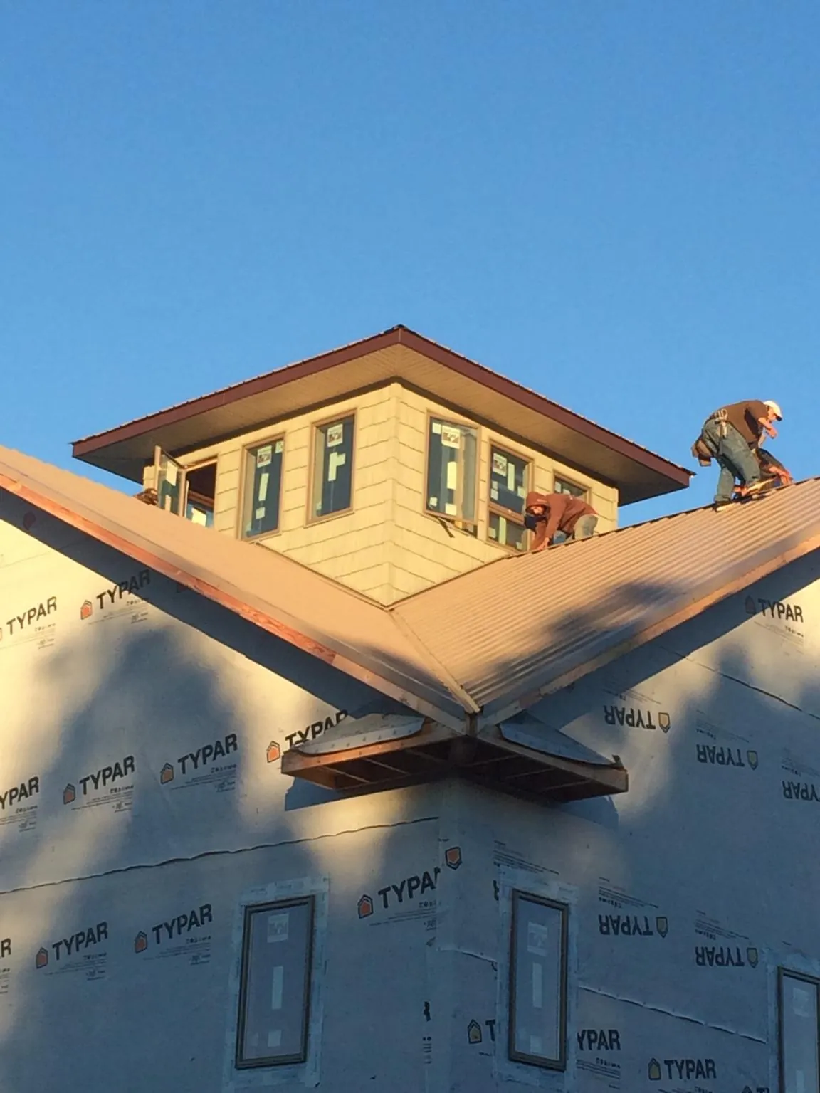 Roofers working around a rooftop cupola on a new metal roof at sunset — Roof Waterproofing in De Mossville by Roofing Brothers